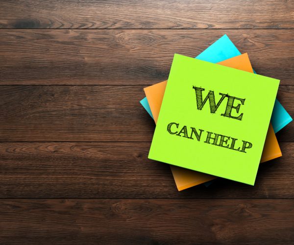 We Can Help, the phrase is written on multi-colored stickers, on a brown wooden background. Business concept, strategy, plan, planning.